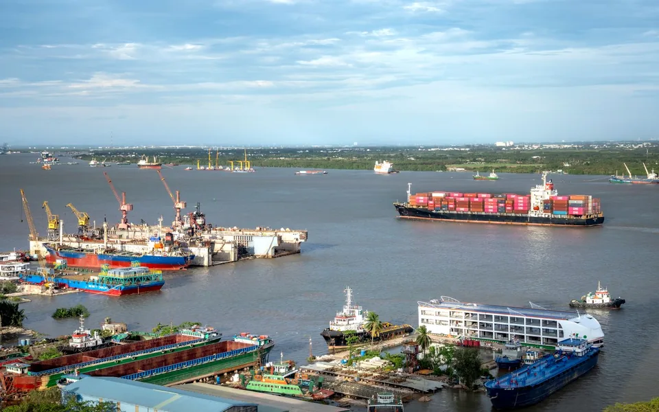 Cargo vessels and port cranes along a busy shipping waterway